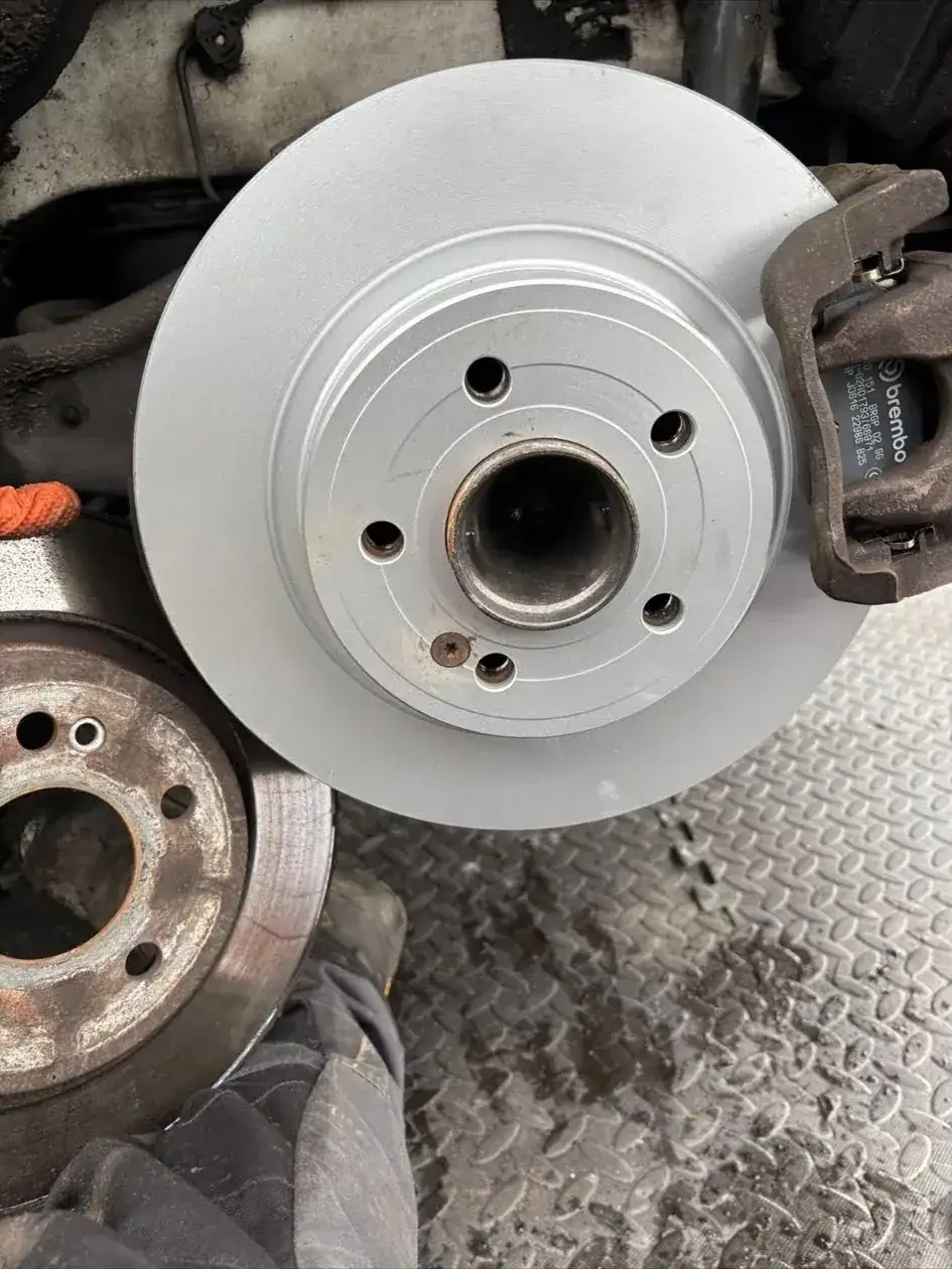 Close-up of a new brake disc and Brembo caliper fitted during a mobile brake repair