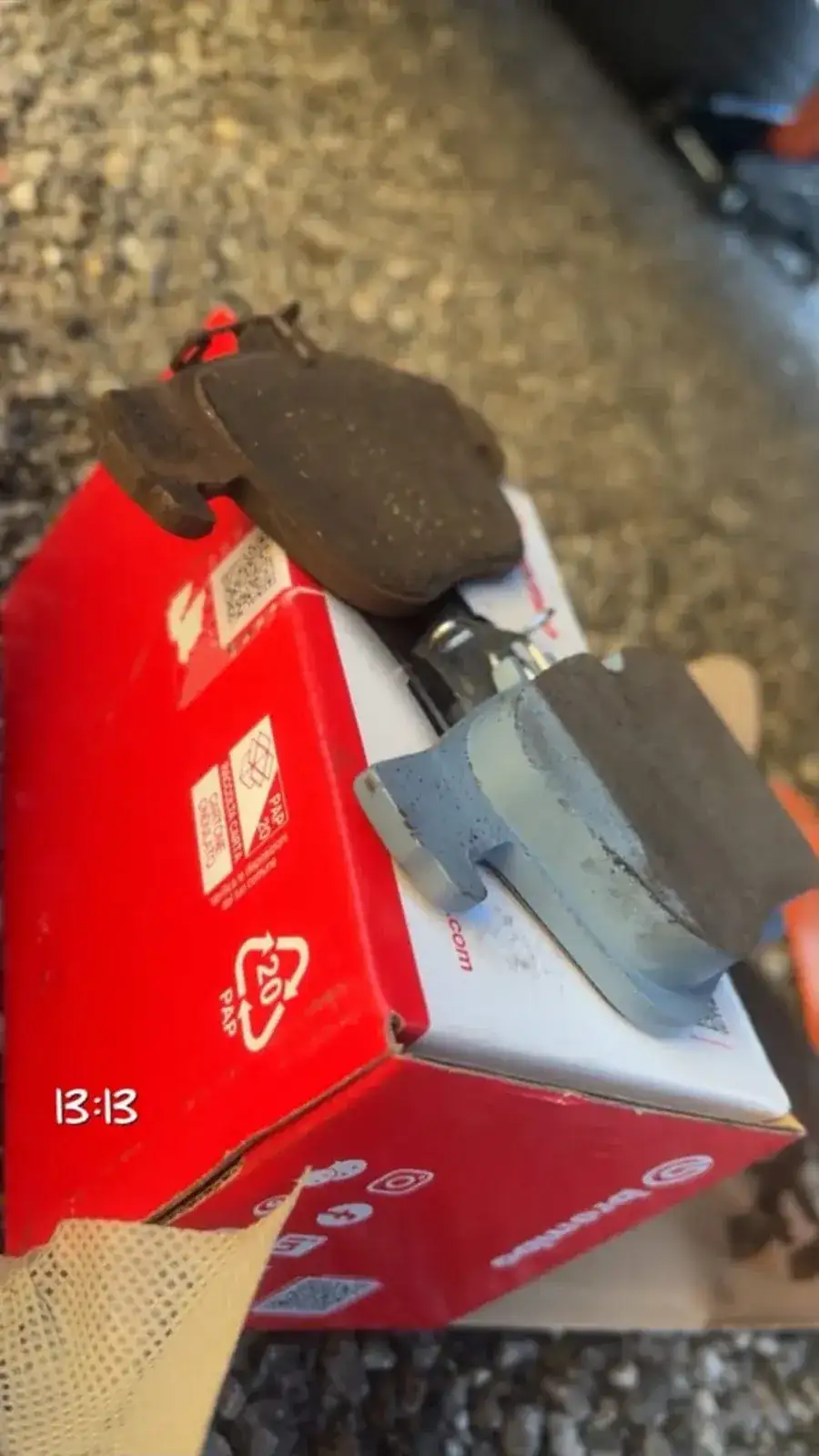 Worn brake pads next to a box of new Brembo replacements
