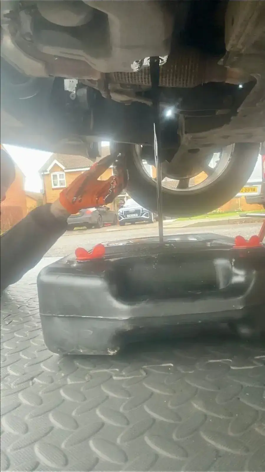 Mechanic draining old oil from a car into a catch container