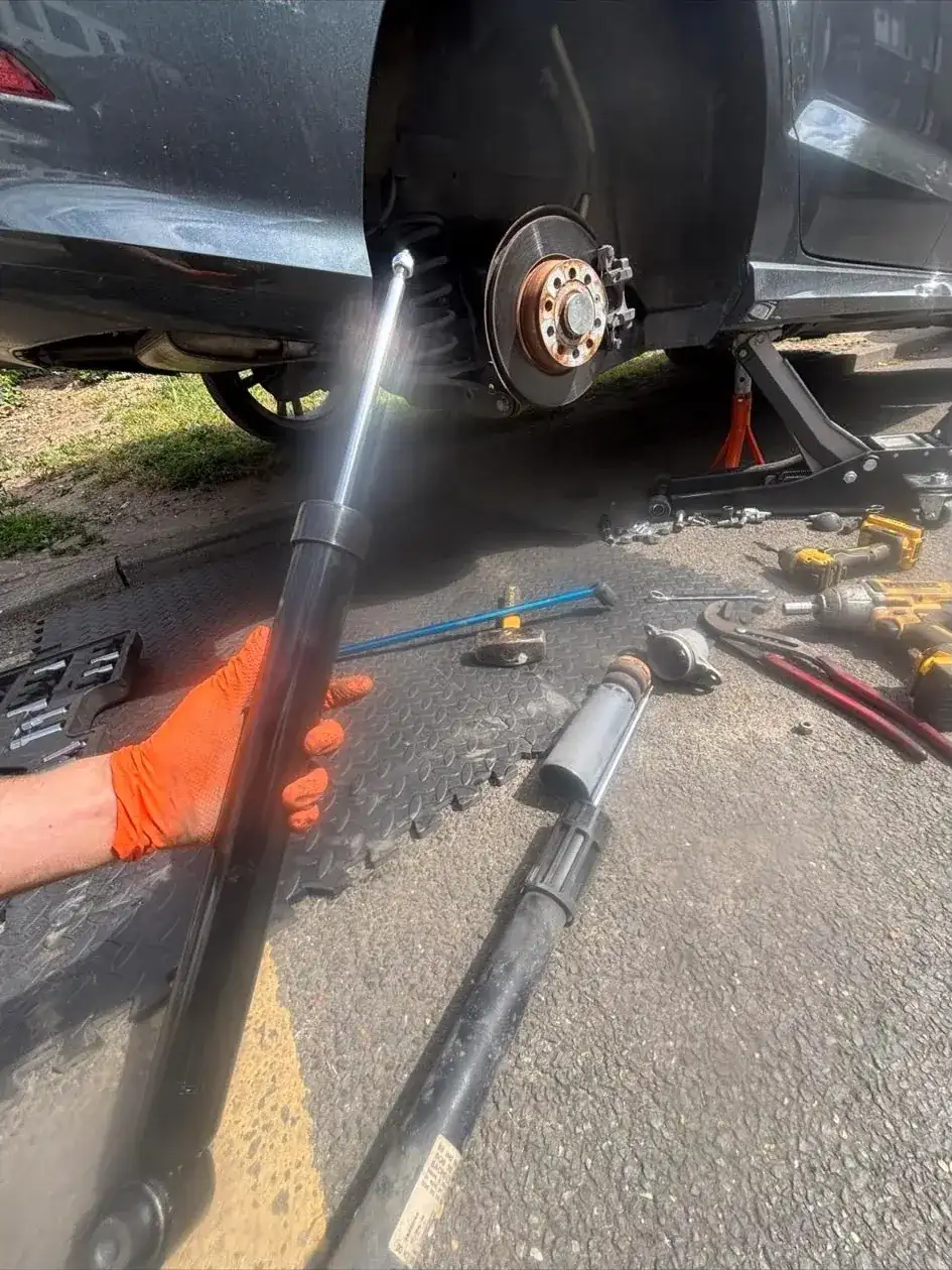 Mechanic holding a replacement shock absorber next to a raised car