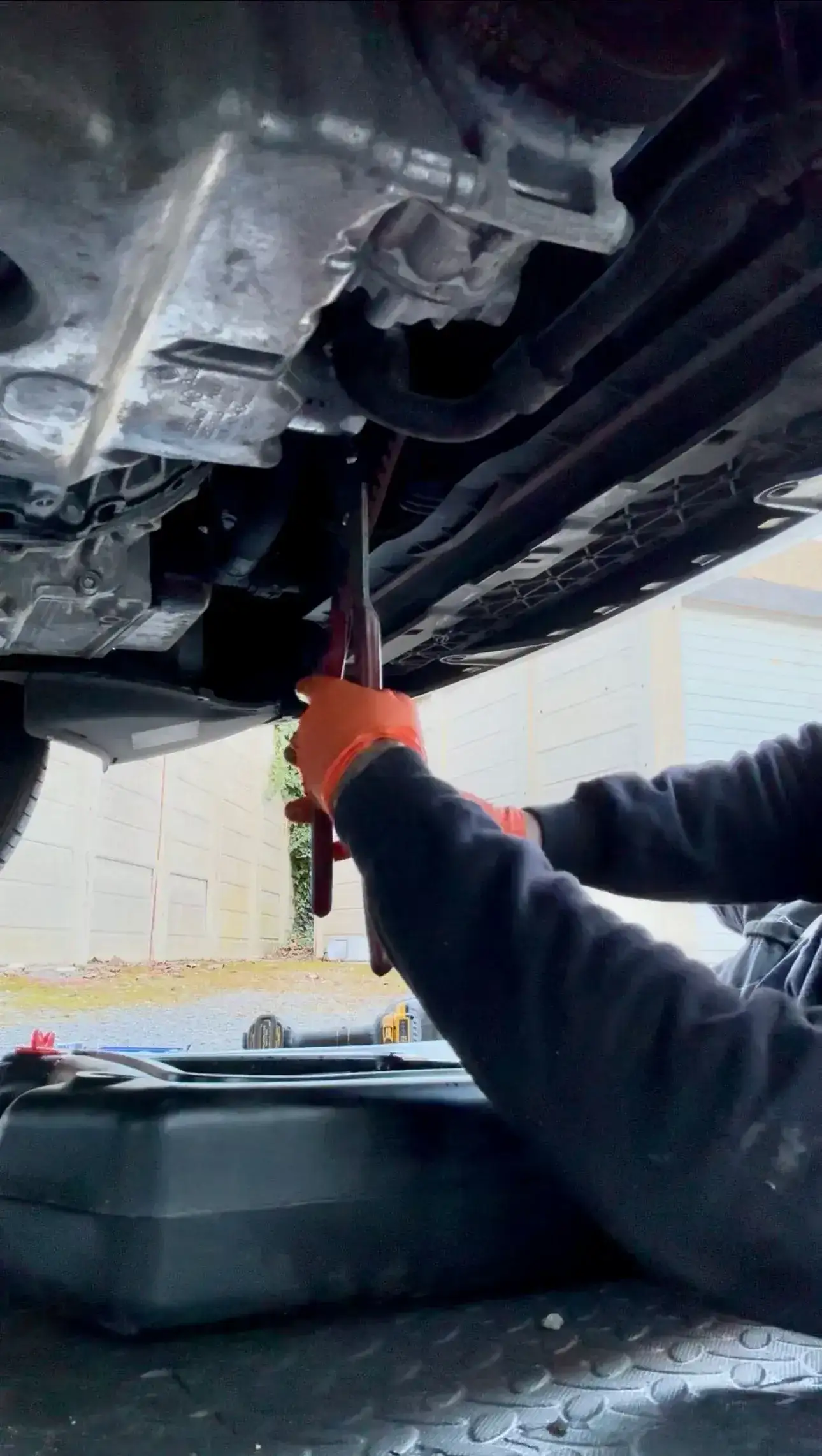 Mechanic working underneath a car with a pry bar during a mobile repair
