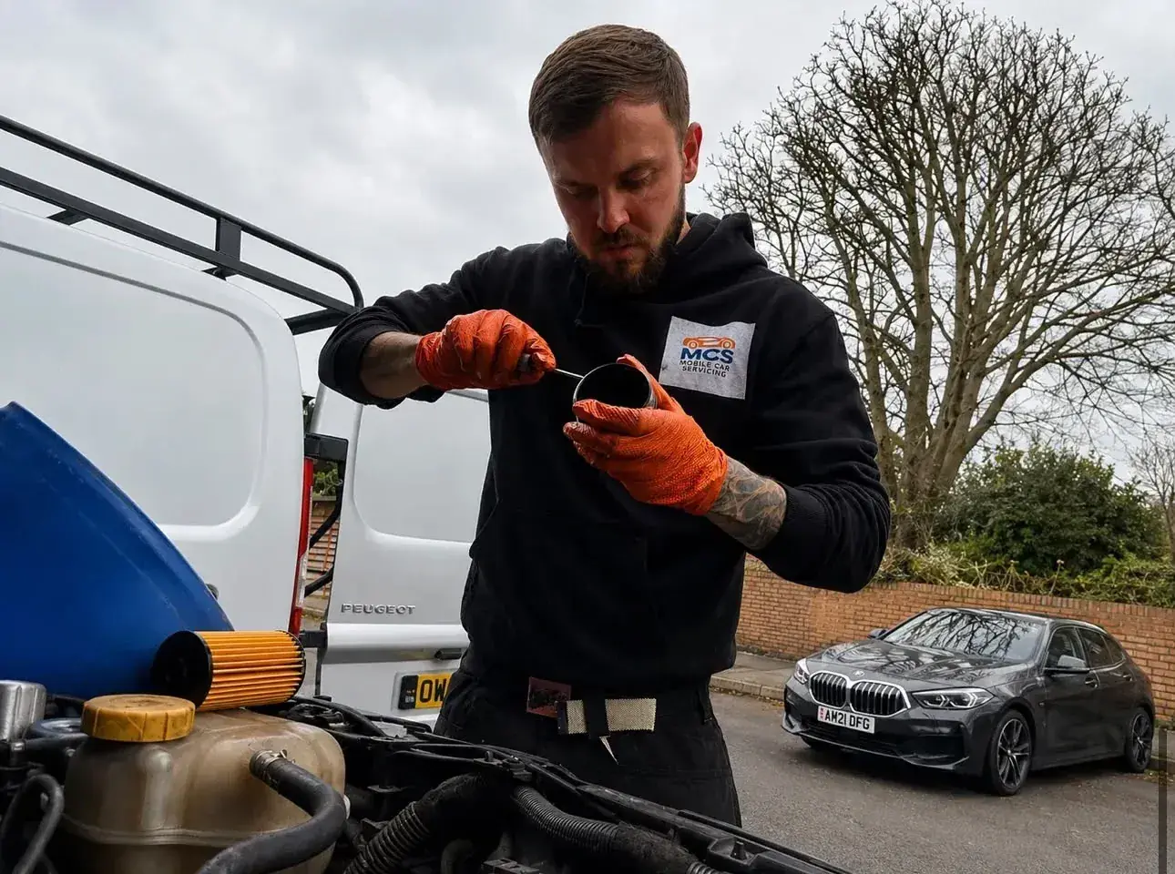 Mechanic replacing an oil filter beside his van during a mobile car service