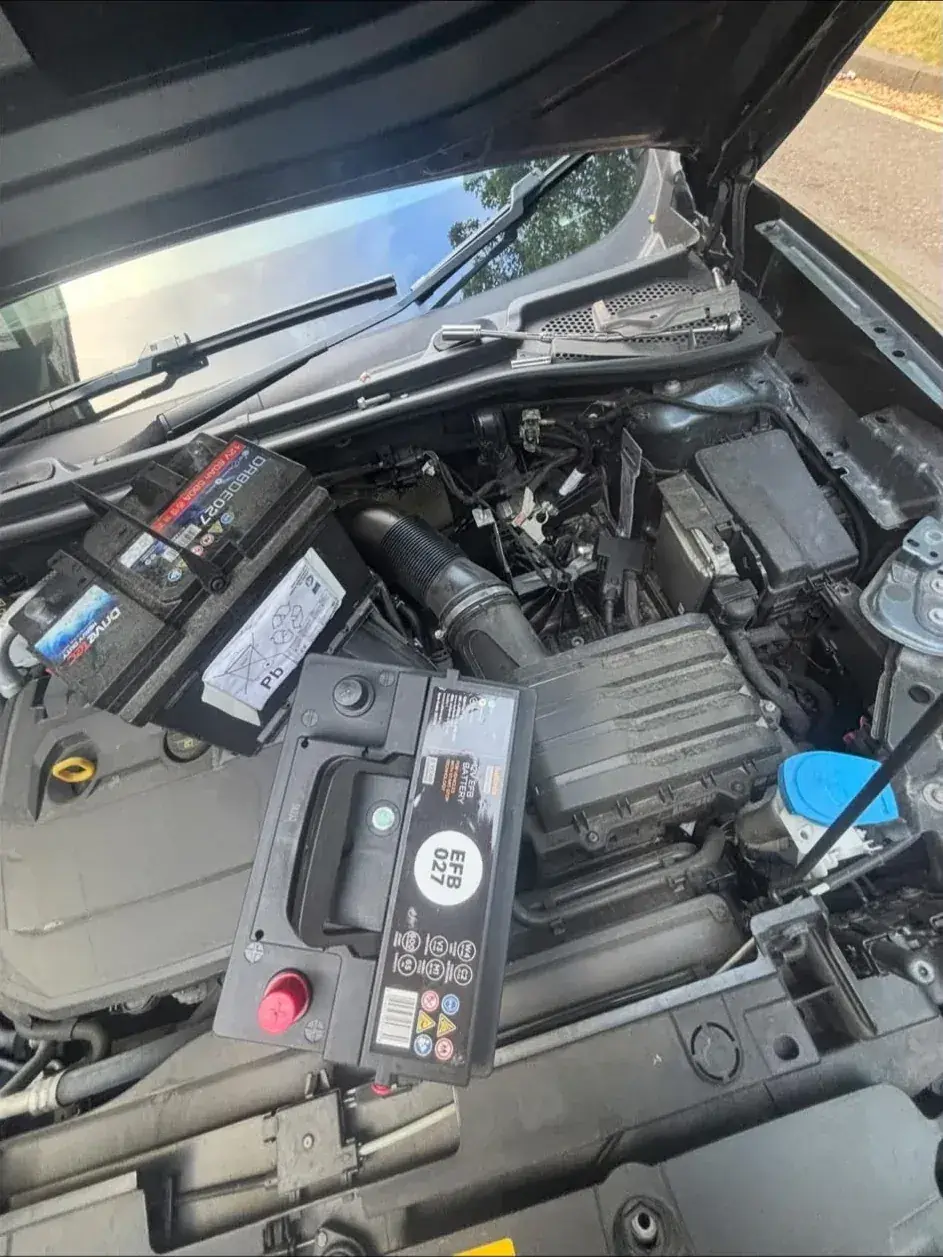 New car battery being fitted in an engine bay during a mobile battery replacement